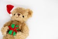 A stuffed toy Teddy bear in a red Santa Claus hat with a pompom on one ear, holding green gift boxes Royalty Free Stock Photo
