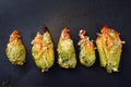 stuffed zucchini or courgette flowers in a row baked with parmesan cheese on a dark baking tray, high angle view from above, copy