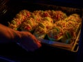 Stuffed zucchini with minced meat, tomatoes and cheese. Woman puts baking sheet with dish in oven for baking. Healthy Royalty Free Stock Photo