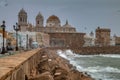 Stuning cityscape with the cathedral of Cadiz next to a rough sea