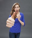 Stunned beautiful young woman agreeing with a large thumbs up