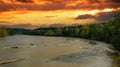 A stunning aerial shot of the Chattahoochee river surrounded by lush green and autumn colored trees with powerful red clouds Royalty Free Stock Photo