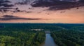 A stunning aerial shot of the Chattahoochee river surrounded by lush green and autumn colored trees with powerful red clouds Royalty Free Stock Photo