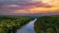 A stunning aerial shot of the Chattahoochee river surrounded by lush green and autumn colored trees with powerful red clouds Royalty Free Stock Photo