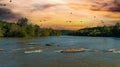 A stunning aerial shot of the Chattahoochee river surrounded by lush green and autumn colored trees with powerful red clouds Royalty Free Stock Photo