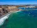 A stunning aerial shot of the deep blue ocean water and the sandy beach and the boats on the harbor Royalty Free Stock Photo