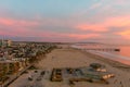 A stunning aerial shot of a gorgeous orange and red sunset over the ocean at the beach with powerful clouds and waves