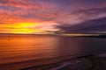 A stunning aerial shot of a gorgeous orange and red sunset over the ocean at the beach with powerful clouds and waves Royalty Free Stock Photo