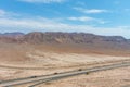 A stunning aerial shot of majestic mountain ranges in a vast desert land with powerful clouds with freeways