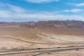 A stunning aerial shot of majestic mountain ranges in a vast desert land with powerful clouds with freeways