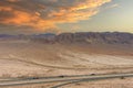 A stunning aerial shot of majestic mountain ranges in a vast desert land with powerful clouds with freeways