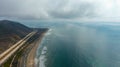 A stunning aerial shot of the vast smooth ocean water along the coastline with a thick powerful cloud cover at Rincon Beach