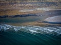 Stunning aerial view of a beach and dark teal ocean waves.