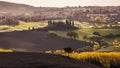 Stunning autumn morning Tuscany hills landscape with plowed and green grass covered beautiful wavy fields. Sunrise light covering Royalty Free Stock Photo