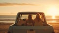 Two girls sitting on back of ute at beach Royalty Free Stock Photo