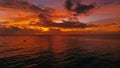 Stunning beautiful aerial drone image of a red tropical sunset above the sea ocean with two man in a canoe fishing