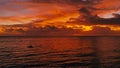 Stunning beautiful aerial drone image of a red tropical sunset above the sea ocean with two man in a canoe fishing