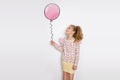 Stunning beautiful little girl with long blond hair standing on a white background and holds a balloon Royalty Free Stock Photo