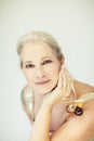 Stunning beautiful and self confident best aged woman with grey hair smiling into camera, holding Christmas decoration baubles Royalty Free Stock Photo