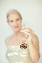 Stunning beautiful and self confident best aged woman with grey hair smiling into camera, holding Christmas decoration baubles Royalty Free Stock Photo