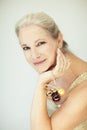 Stunning beautiful and self confident best aged woman with grey hair smiling into camera, holding Christmas decoration baubles