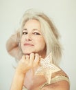 Stunning beautiful and self confident best aged woman with grey hair smiling into camera, holding Christmas decoration star Royalty Free Stock Photo