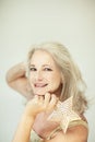 Stunning beautiful and self confident best aged woman with grey hair smiling into camera, holding Christmas decoration star Royalty Free Stock Photo