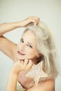 Stunning beautiful and self confident best aged woman with grey hair smiling into camera, holding Christmas decoration star Royalty Free Stock Photo