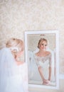 Stunning blonde bride looks in white mirror