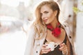 Stunning blonde lady with red neckerchief enjoying good day and driking tasty latte. Outdoor portrait of glad