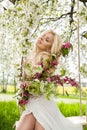 Stunning blonde natural woman swing on a swing on a tree wearing a spring dress Royalty Free Stock Photo