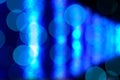 Bokeh - brilliant rows of glowing white light merging with circular orbs of reflections emerging from a deep blue background.