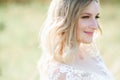 Stunning bride with white curls stands on the field in a sunny day