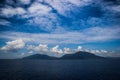 Stunning bright and rich dark blue sky with clouds, mountains and ocean