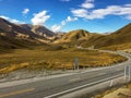 The stunning brown landscape of the rolling hills and mountains of the Lindis Pass, New Zealand with a road weaving through the Royalty Free Stock Photo