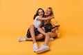Stunning brunette girl in white shoes embracing her sister with happy smile. Carefree blonde lady having fun with best Royalty Free Stock Photo