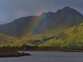 Rainbow above characteristic wooden houses with red painted facade in small village on coast of VestvÃÂ¥gÃÂ¸y, Lofoten, Norway. Royalty Free Stock Photo