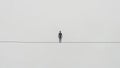 A Man Walking on a Tightrope in a White Background (Balance, Equilibrium, Resilience, Difficult Situation Metaphor) Royalty Free Stock Photo