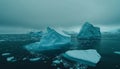 A stunning display of massive icebergs rises from a tranquil sea, framed by dark clouds and a fading light at twilight Royalty Free Stock Photo