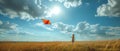 In a stunning display of simplicity and joy, a child flies an orange kite under a sky dotted with clouds.