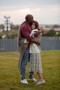 Stunning diverse couple standing in park, embraced in love, wrapped in warm blanket. Affectionate moment between African American