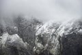 Stunning dramatic landscape image of snowcapped Glyders mountain range in Snowdonia during Winter with menacing low clouds hanging