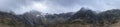 Stunning dramatic panoramic landscape image of snowcapped Glyders mountain range in Snowdonia during Winter with menacing low