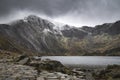 Beautiful moody Winter landscape image of Llyn Idwal and snowcapped Glyders Mountain Range in Snowdonia