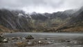 Beautiful moody Winter landscape image of Llyn Idwal and snowcapped Glyders Mountain Range in Snowdonia