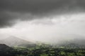Stunning epic landscape image across Derwentwater valley with falling rain drifting across the mountains causing pokcets of light Royalty Free Stock Photo