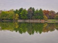 Stunning Fall Scene of Autumn Colored Trees Lining Lake, Bright Blue Sky with Streaking Clouds All Reflected in Calm Water Calm Royalty Free Stock Photo