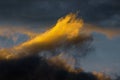 Stunning fluffy thunderstorm clouds illuminated by disappearing rays at sunset, dark thunderclouds floating across blue