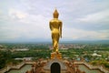 Stunning gold colored Buddha image in walking posture facing the town of Nan, Wat Phra That Khao Noi temple, Thailand Royalty Free Stock Photo