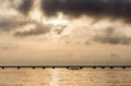 Stunning golden sunset over the sea. Silhouette of Dragon boat in the sea. A beautiful bridge on the horizon and amazing clouds in Royalty Free Stock Photo